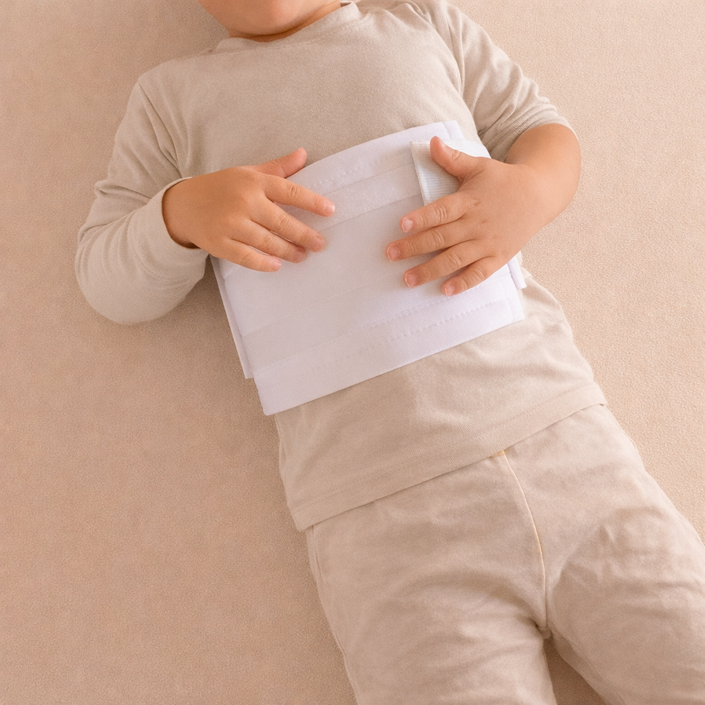 Young child lying down, wearing a white castor oil pack.
